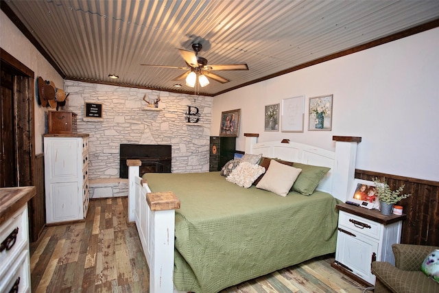 bedroom featuring wood-type flooring, wood ceiling, ornamental molding, and a fireplace