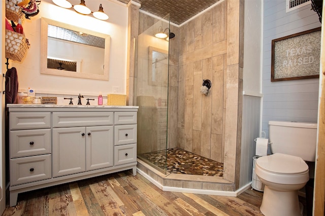 bathroom featuring a tile shower, vanity, toilet, and hardwood / wood-style flooring