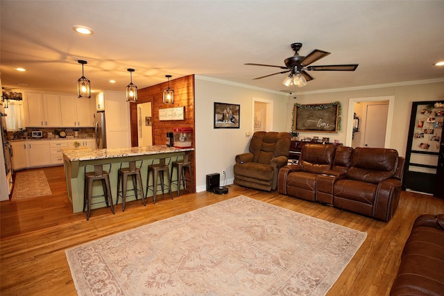 living room featuring light hardwood / wood-style flooring, ceiling fan, and ornamental molding