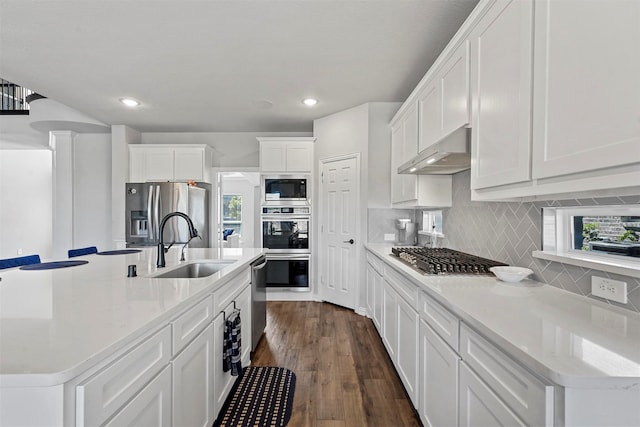 kitchen with dark hardwood / wood-style floors, a center island with sink, appliances with stainless steel finishes, sink, and white cabinets