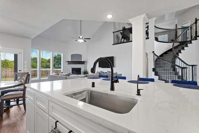 kitchen featuring hardwood / wood-style floors, white cabinetry, sink, ceiling fan, and vaulted ceiling