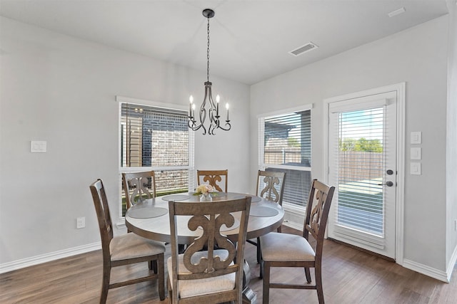 dining space with dark wood-type flooring and a notable chandelier