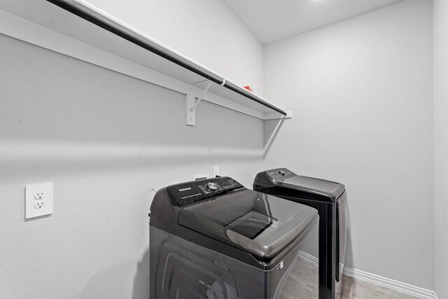 laundry area featuring washing machine and dryer and hardwood / wood-style flooring