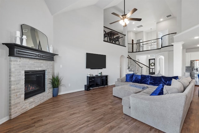 living room featuring high vaulted ceiling, ceiling fan, hardwood / wood-style flooring, and a brick fireplace