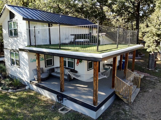 back of house with a standing seam roof, metal roof, fence, a balcony, and a yard