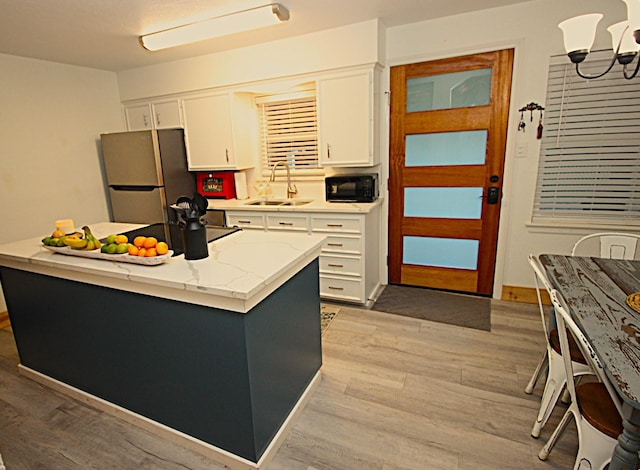 kitchen with freestanding refrigerator, white cabinetry, a sink, light wood-type flooring, and black microwave