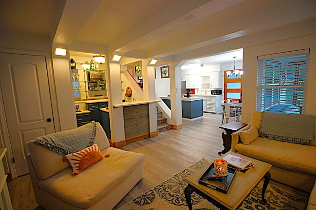 living area with light wood-type flooring, a notable chandelier, and stairs