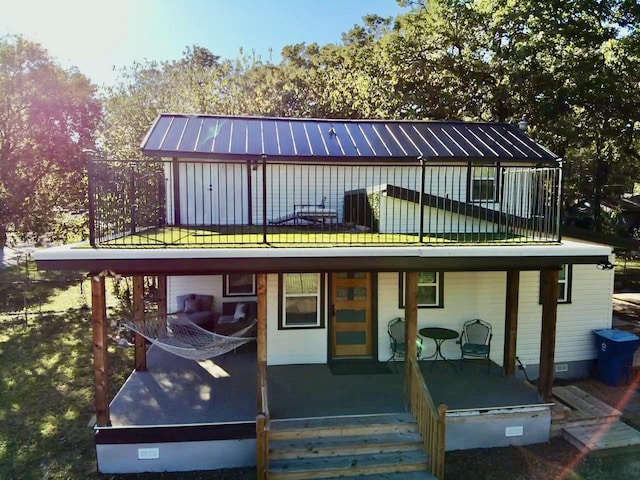 rear view of house featuring a standing seam roof, covered porch, metal roof, and crawl space