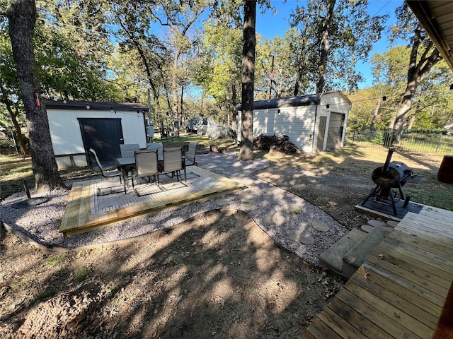 view of yard featuring an outbuilding, outdoor dining area, a patio, fence, and a shed