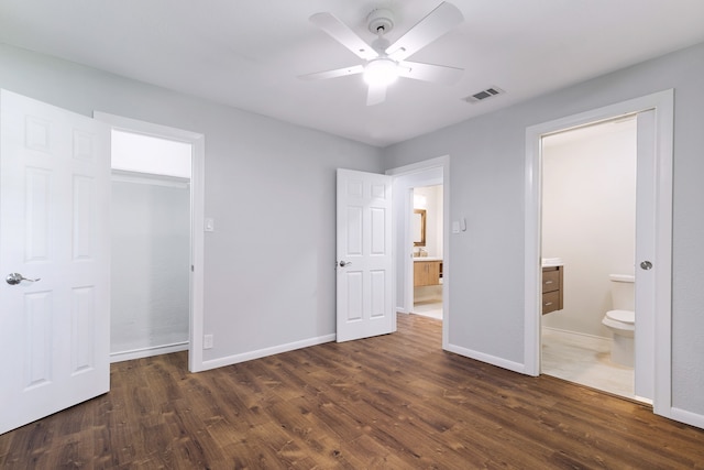 unfurnished bedroom featuring ceiling fan, dark wood-type flooring, ensuite bath, and a closet