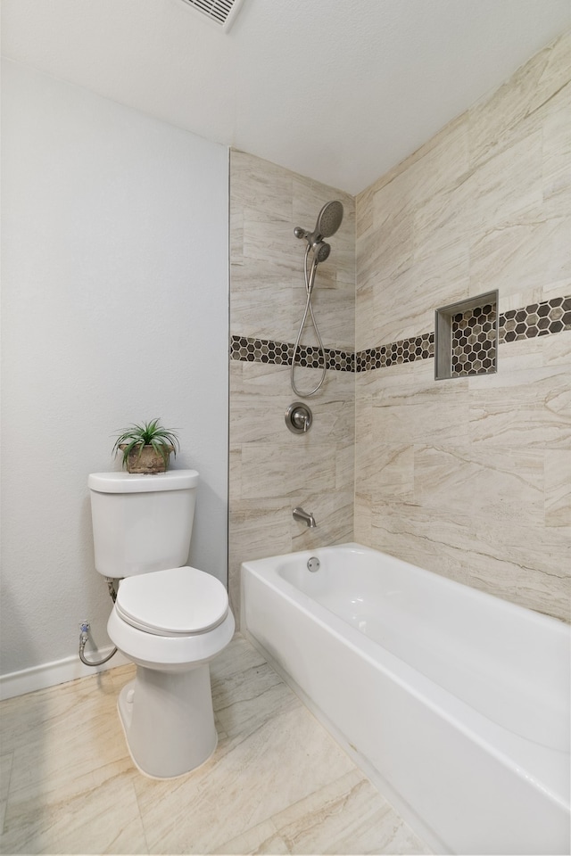 bathroom with tiled shower / bath combo and toilet