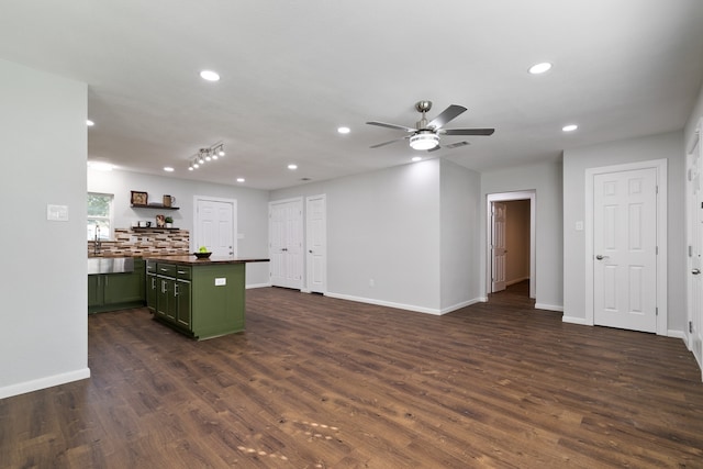 kitchen with ceiling fan, sink, green cabinetry, dark hardwood / wood-style floors, and decorative backsplash