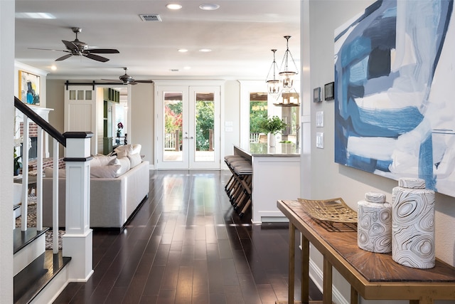 living room featuring french doors, a barn door, dark hardwood / wood-style floors, and an inviting chandelier