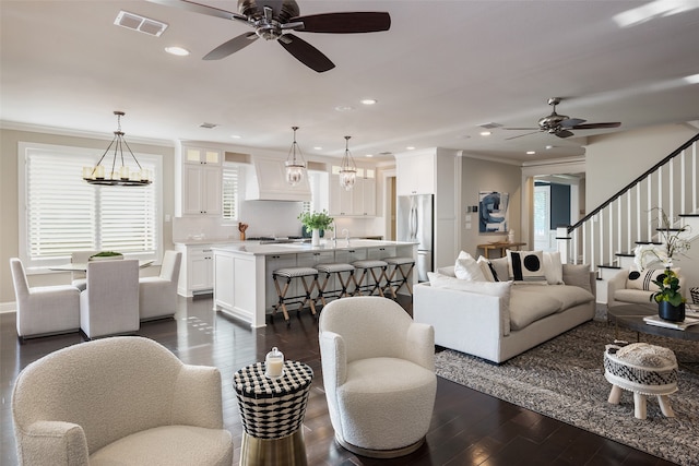 living room featuring sink, dark wood-type flooring, ceiling fan with notable chandelier, and ornamental molding