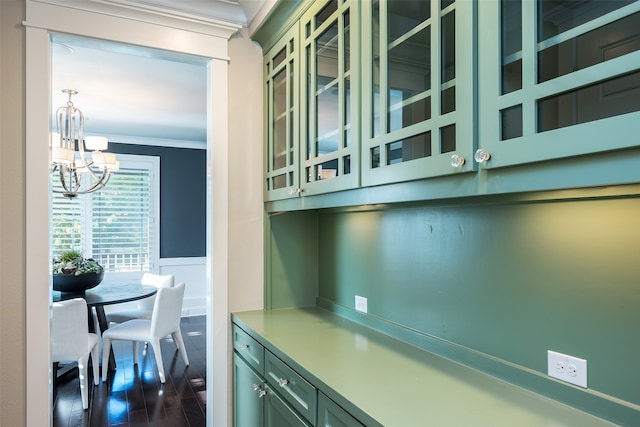 bar with a chandelier, dark hardwood / wood-style floors, green cabinetry, and ornamental molding