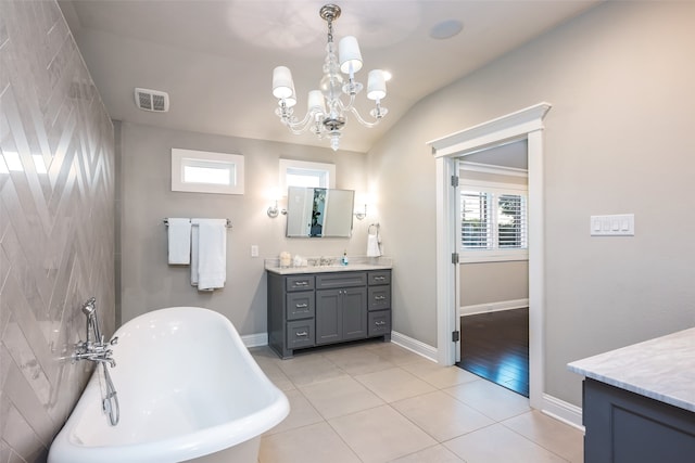 bathroom featuring a bathtub, vanity, lofted ceiling, tile patterned flooring, and a notable chandelier