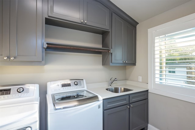 clothes washing area with washer and dryer, cabinets, and sink