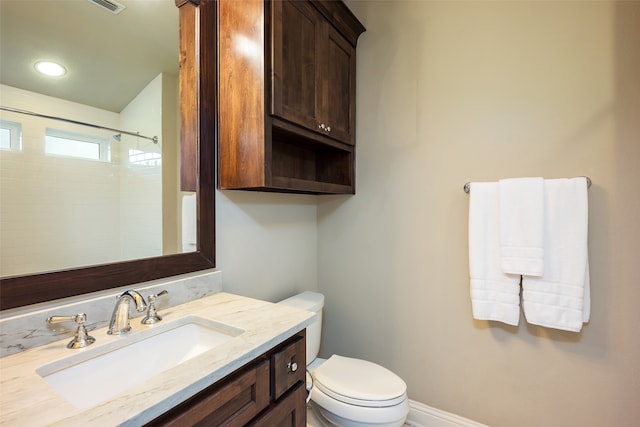 bathroom with vanity, toilet, and a tile shower