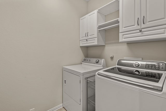 laundry room featuring washer and clothes dryer and cabinets