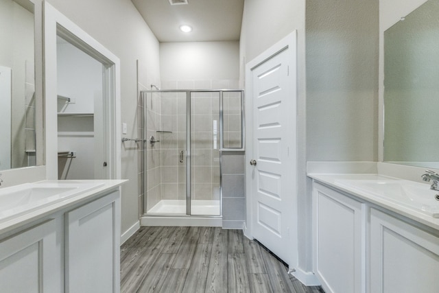 bathroom with hardwood / wood-style floors, a shower with door, and vanity