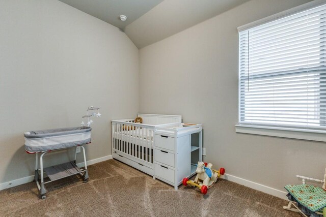 bedroom featuring lofted ceiling, a crib, and carpet floors