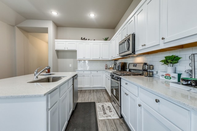 kitchen featuring appliances with stainless steel finishes, sink, light stone countertops, and light hardwood / wood-style floors