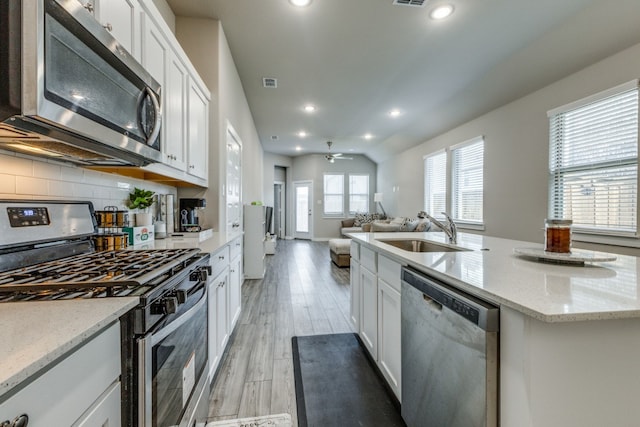 kitchen featuring white cabinetry, an island with sink, sink, appliances with stainless steel finishes, and light hardwood / wood-style floors