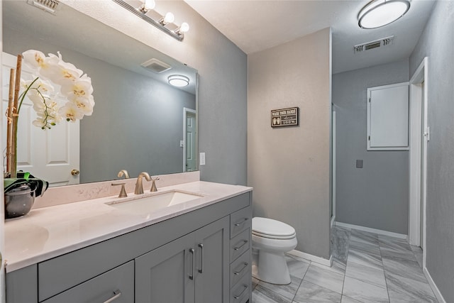 bathroom with vanity, toilet, and a shower with door