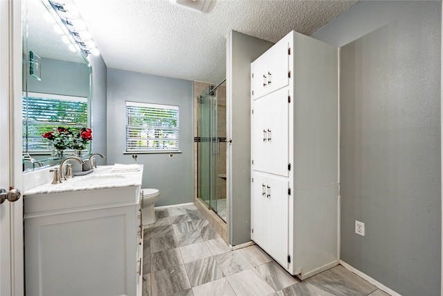 bathroom featuring vanity, a shower with shower door, toilet, and a textured ceiling