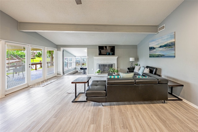 living room featuring vaulted ceiling with beams, a textured ceiling, hardwood / wood-style floors, and a fireplace