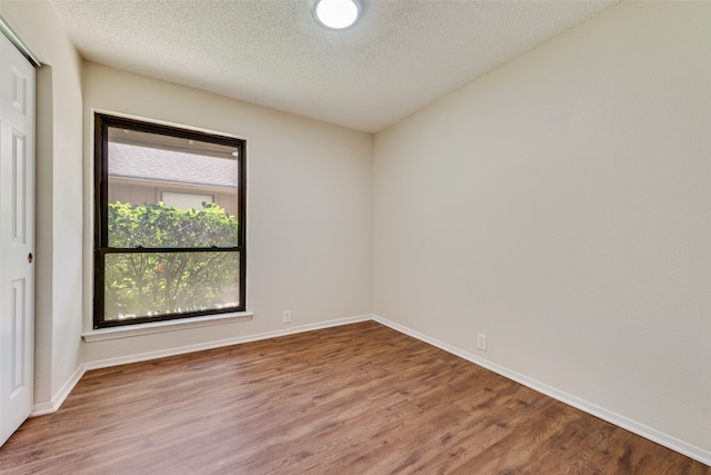 empty room featuring wood-type flooring and a textured ceiling