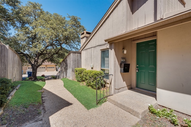 property entrance with a garage and a lawn