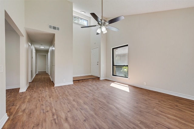 unfurnished living room with high vaulted ceiling, ceiling fan, and wood-type flooring