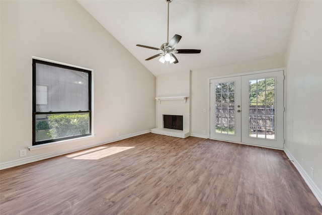 unfurnished living room with a fireplace, high vaulted ceiling, hardwood / wood-style floors, ceiling fan, and french doors