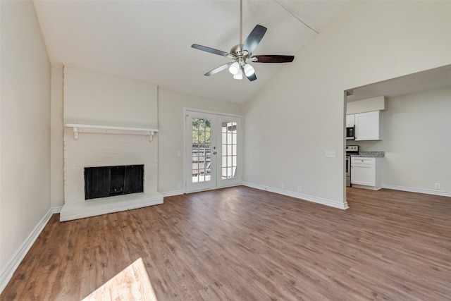 unfurnished living room with vaulted ceiling, a fireplace, wood-type flooring, french doors, and ceiling fan