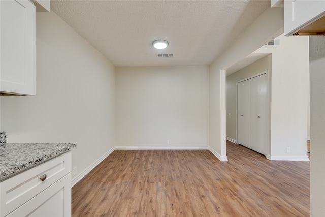 unfurnished room with light wood-type flooring and a textured ceiling