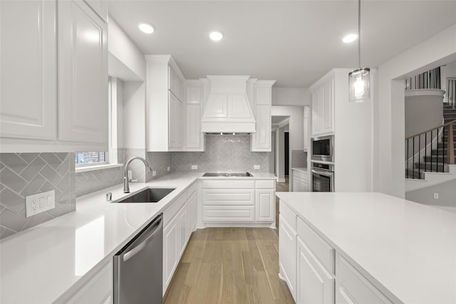 kitchen with white cabinetry, sink, premium range hood, and stainless steel appliances