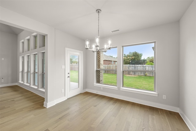 unfurnished dining area featuring a chandelier and light wood-type flooring