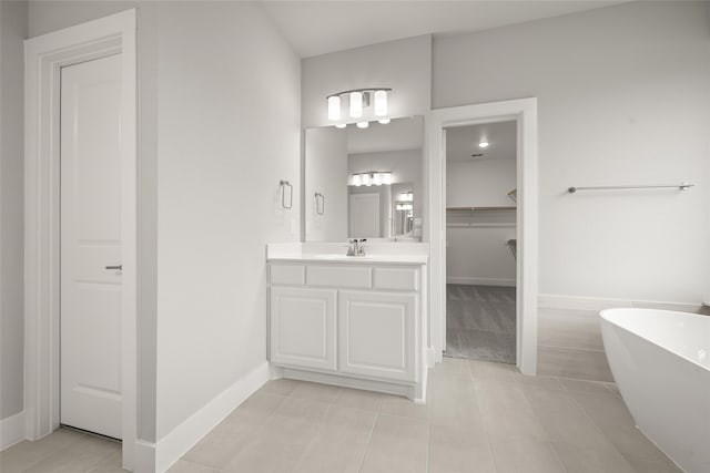 bathroom with a bathing tub, vanity, and tile patterned floors