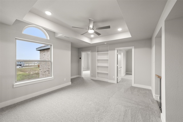 unfurnished bedroom featuring light colored carpet, ceiling fan, and a tray ceiling