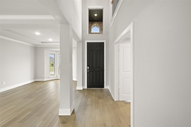 entryway featuring light hardwood / wood-style floors, a high ceiling, and ornamental molding