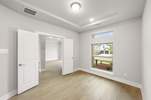 unfurnished bedroom with light hardwood / wood-style floors and a raised ceiling