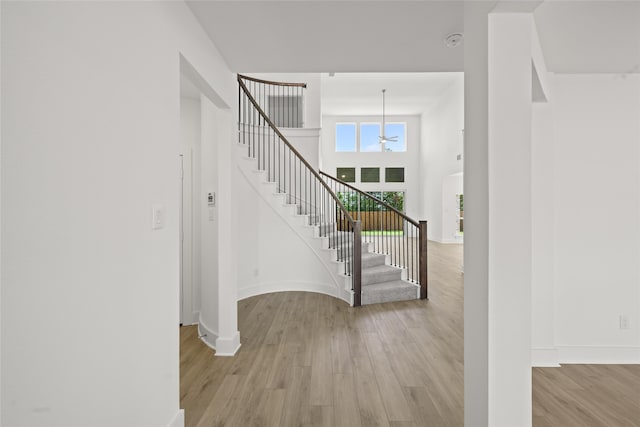 entrance foyer with light hardwood / wood-style flooring, a towering ceiling, and an inviting chandelier