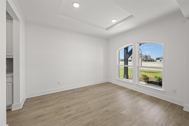 empty room featuring ornamental molding, light hardwood / wood-style flooring, and a raised ceiling