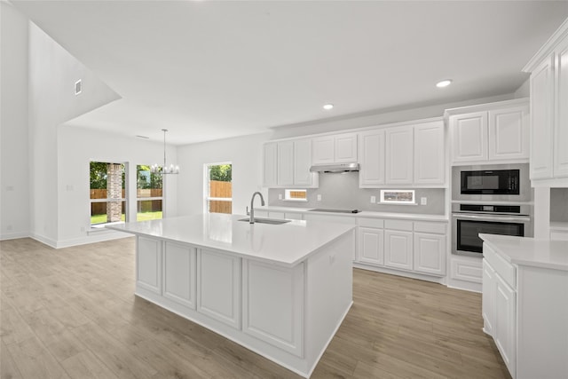 kitchen featuring sink, a center island with sink, white cabinetry, stainless steel oven, and light wood-type flooring