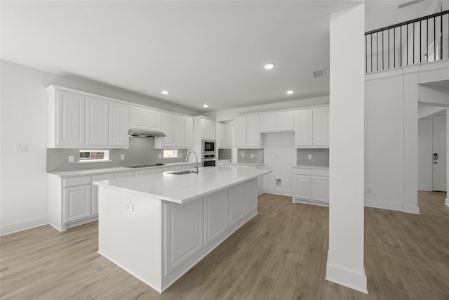 kitchen with a kitchen island with sink, sink, and white cabinets