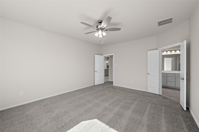 unfurnished bedroom with ensuite bathroom, light colored carpet, and ceiling fan