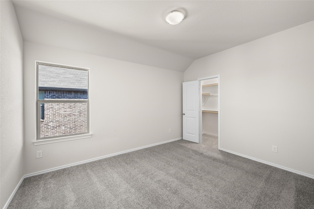 unfurnished bedroom with carpet floors, vaulted ceiling, and a walk in closet