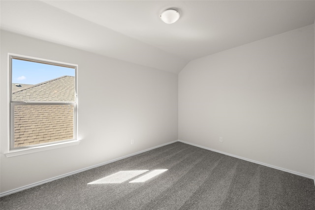 unfurnished room with lofted ceiling and dark colored carpet