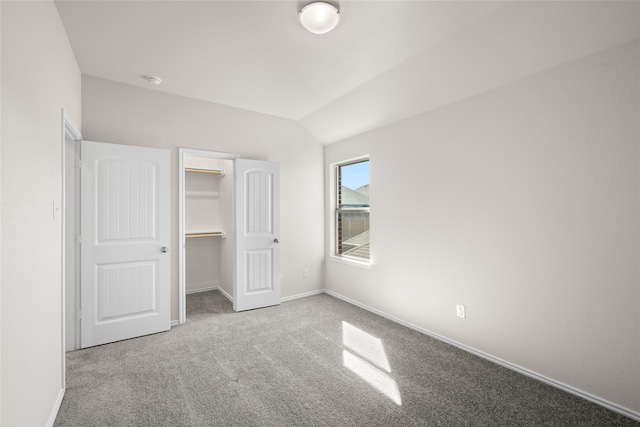 unfurnished bedroom featuring a spacious closet, carpet floors, a closet, and lofted ceiling